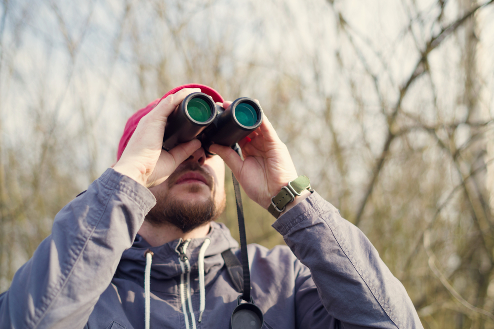 A man using binoculars while watching birds